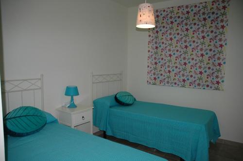 2 Betten in einem Zimmer mit blauer Bettwäsche und einem Fenster in der Unterkunft Apartamento Costa Ballena in Chipiona