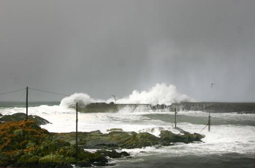 a large wave in the ocean with people surfing at Laukvik Suites in Laukvik