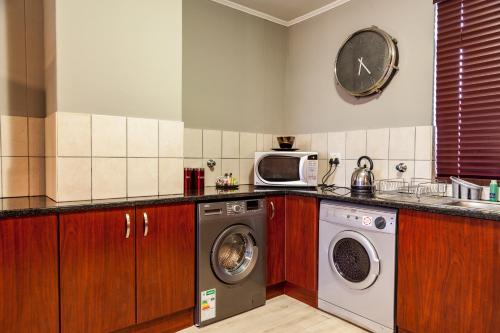 a kitchen with a washing machine and a clock on the wall at Island Club Hotel & Apartments in Cape Town