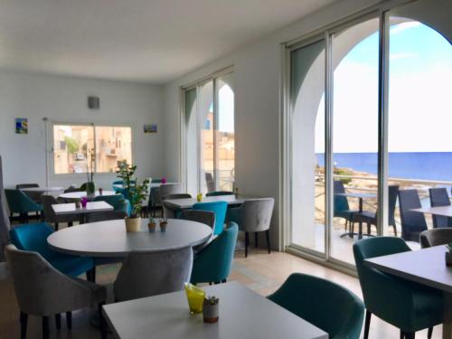 a restaurant with tables and chairs and a view of the ocean at Hotel de la Plage Santa Vittoria in Algajola