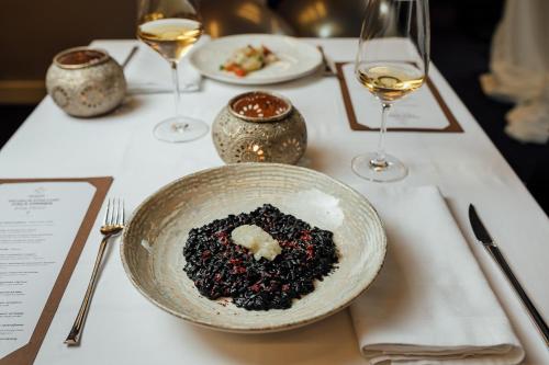 a plate of food on a table with wine glasses at Boutique Hotel & Spa Casa del Mare - Mediterraneo in Herceg-Novi