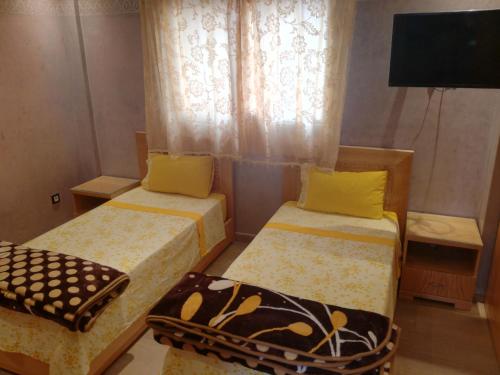 a room with two beds and a tv and a window at Genova surf house in Imsouane