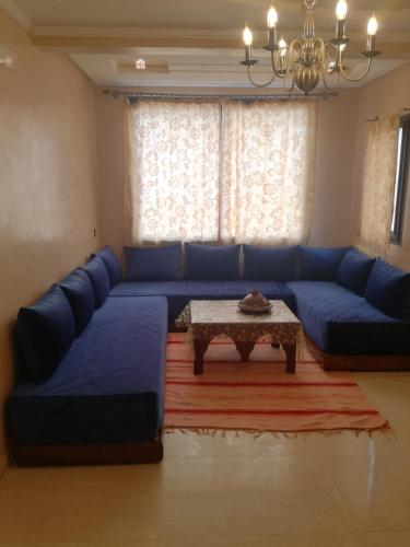 a living room with a blue couch and a table at Genova surf house in Imsouane