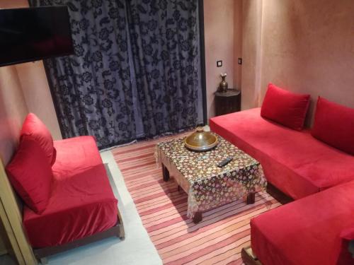 a living room with two red couches and a table at Genova surf house in Imsouane