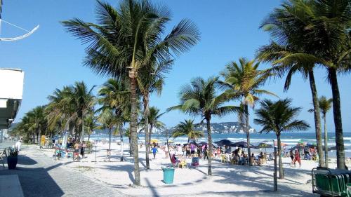 a beach with palm trees and a crowd of people at Apto Praia da Enseada 4 pessoas in Guarujá