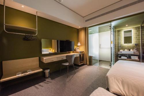 a hotel room with a bed and a desk and a television at Ramble Hotel in Taichung