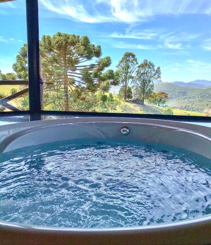 a jacuzzi tub with a view of the mountains at Chalés Encanto Das Pedras - Chalé Super Luxo in Sapucaí-Mirim