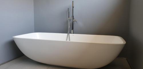 a white bath tub with a faucet in a bathroom at Serrulata House in Hermanus