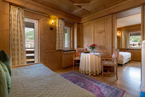 a room with a table and a bed and a bedroom at Hotel Baita Dei Pini in Bormio