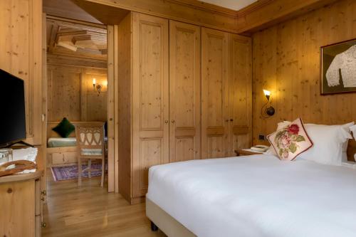 a bedroom with a white bed and a television at Hotel Baita Dei Pini in Bormio