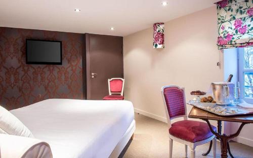 a hotel room with a bed and a table and chairs at Frédéric Carrion - Cuisine, Hôtel & Spa in Viré