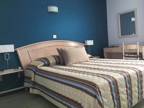 a bedroom with a large bed with a blue wall at Hotel de la Plage Santa Vittoria in Algajola