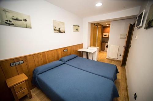 een kleine slaapkamer met een blauw bed en een tafel bij Hostal Caballeros in Soria