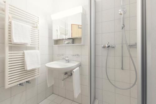 a white bathroom with a shower and a sink at Berghaus Diavolezza in Berninahäuser