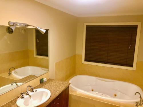 a bathroom with a tub and a sink and a bath tub at Golf View Charm in Craigieburn