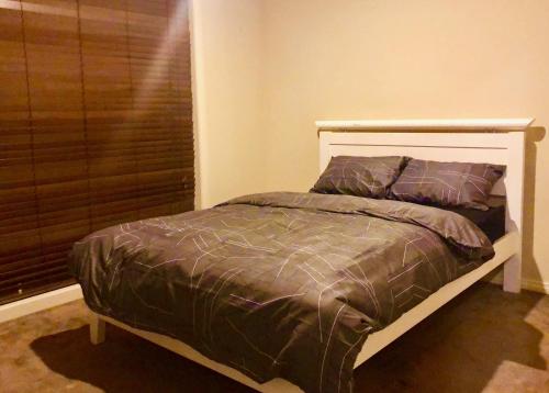 a bed in a bedroom next to a window at Golf View Charm in Craigieburn