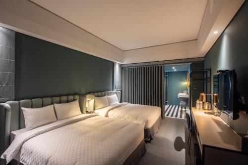 a hotel room with two beds and a television at Ramble Hotel in Taichung