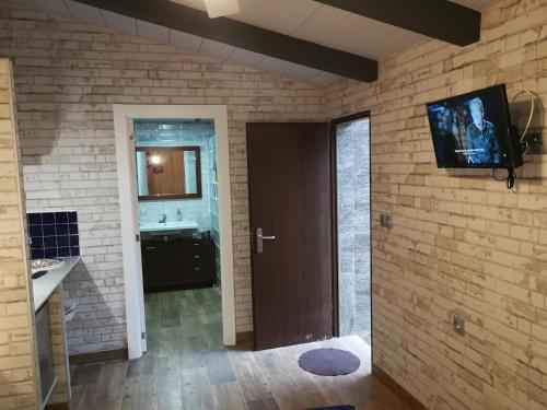 a bathroom with a television on a brick wall at CABAÑA DE MADERA JUNTO AL LAGO LAS JARAS in Córdoba