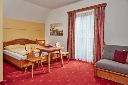 ein Hotelzimmer mit einem Bett, einem Tisch und einem Sofa in der Unterkunft Hotel Domittner in Klöch