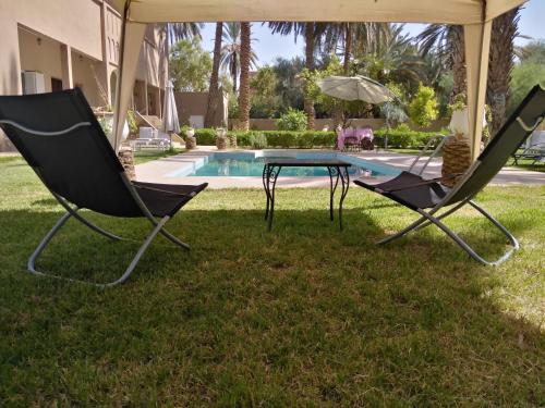 two chairs and a table in front of a pool at Maison d Hôte Ighrem in Goulmima