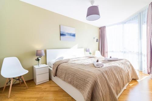 a white bedroom with a bed and a white chair at Elija Swan-Toy Apartments in Šventoji