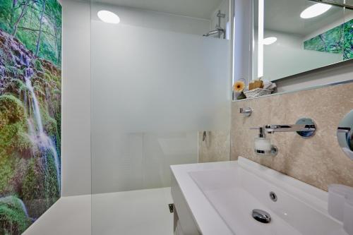 a bathroom with a sink and a waterfall mural at Ringhotel Gasthof Hasen in Herrenberg