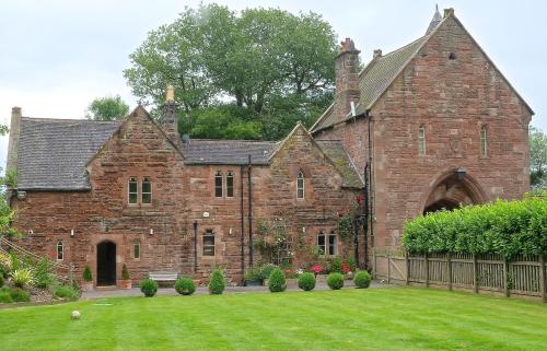 an old brick building with a grass yard at Peckforton Castle in Tarporley
