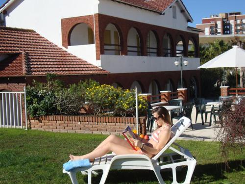 a woman sitting in a lawn chair reading a book at Hotel Morales in San Clemente del Tuyú