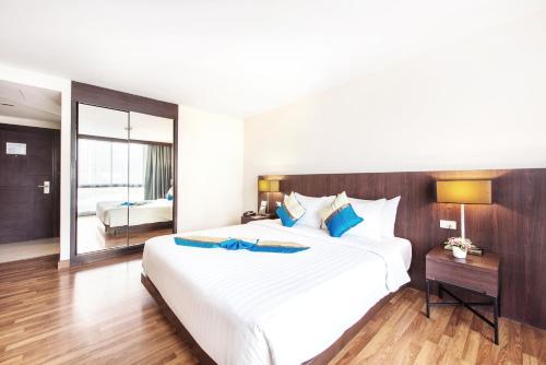 a bedroom with a large white bed with blue pillows at Mida Hotel Ngamwongwan - SHA Plus in Nonthaburi