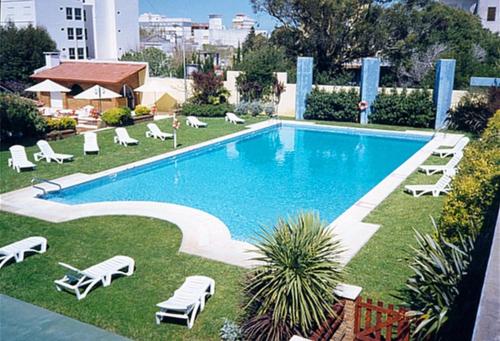 a swimming pool with chaises and lounge chairs around it at Hotel Morales in San Clemente del Tuyú