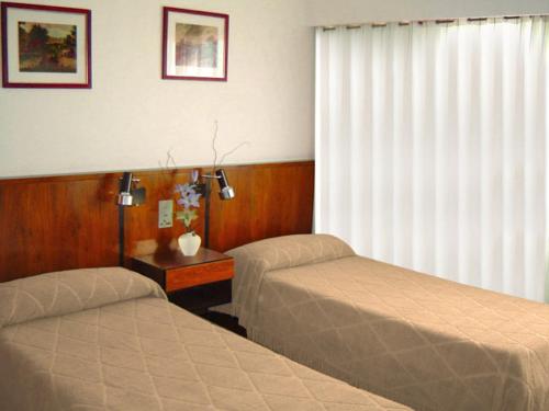 a hotel room with two beds and a window at Hotel Morales in San Clemente del Tuyú