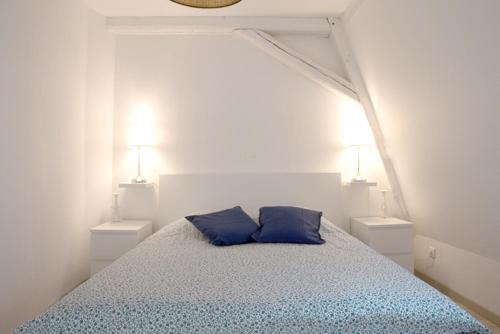 a white bedroom with a bed with two blue pillows at Petite Venise Grand Duplex Turenne Hyper Centre in Colmar