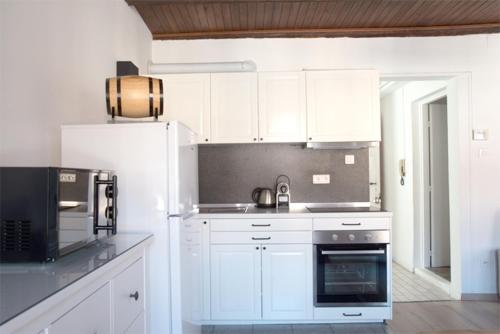 une cuisine avec des armoires blanches et un appareil noir dans l'établissement Petite Venise Grand Duplex Turenne Hyper Centre, à Colmar