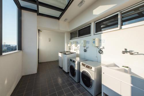a laundry room with three washing machines and a sink at Ramble Hotel in Taichung