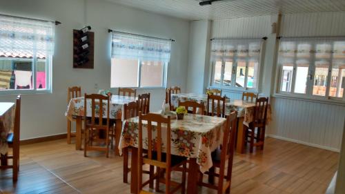 un comedor con mesas, sillas y ventanas en Pousada Amelia, en Urubici