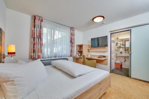 a bedroom with a large white bed and a desk at Ringhotel Gasthof Hasen in Herrenberg
