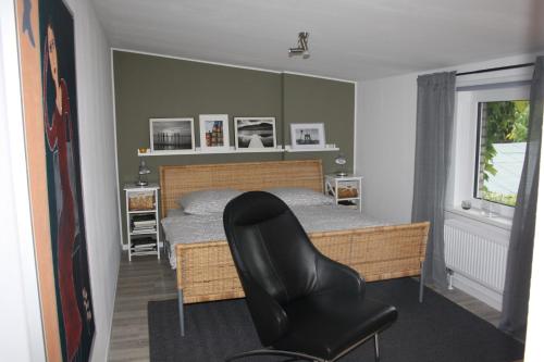 een slaapkamer met een bed en een zwarte stoel bij Ferienwohnungen Harz Wernigerode in Wernigerode