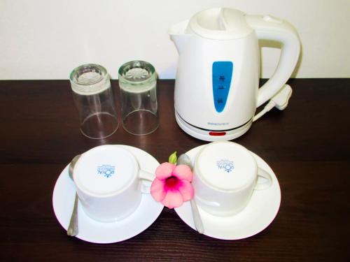una macchinetta del caffè, due tazze e un fiore sul tavolo di Shanika Beach Inn a Tangalle
