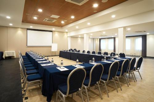 a conference room with tables and chairs and a screen at Eurostars Málaga in Málaga