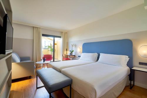 Schlafzimmer mit einem großen Bett mit blauem Kopfteil in der Unterkunft Eurostars Málaga in Málaga