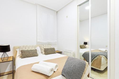 ein weißes Schlafzimmer mit 2 Betten und einem Spiegel in der Unterkunft LEEWAYS APARTMENT XIX in GRAN VÍA in Madrid