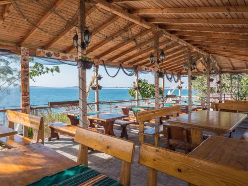 a restaurant with wooden tables and benches and the ocean at Hotel Fantasy Beach in Sveti Vlas