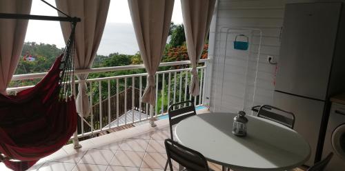 a table and chairs in a room with a large window at GITE REVE CARAIBES LE PETIT HAVRE in Bouillante