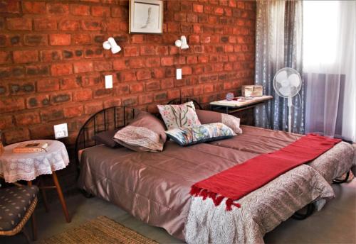 Un dormitorio con una pared de ladrillo y una cama en Aranos Kalahariland Guest Farm, en Aranos