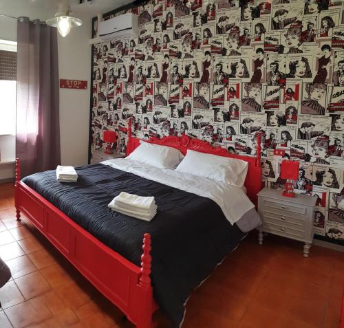 a bedroom with a red bed with a wall of photos at RICCI Rooms in Roccasecca