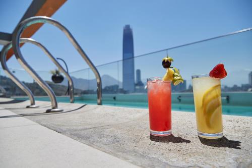 two cocktails sitting on a table next to a pool at Hotel Terrado Providencia in Santiago