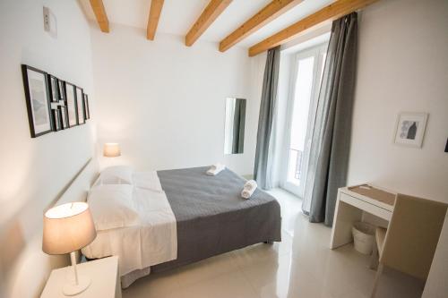 a bedroom with a bed and a desk and a window at Palazzo di Fazio Suites in San Severo