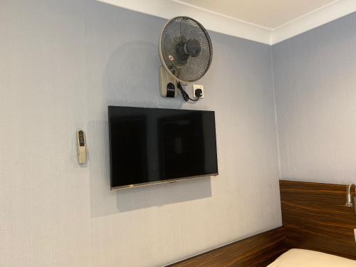 a flat screen tv on a wall with a fan at Crestfield Hotel in London