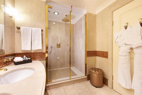 a bathroom with a sink and a shower with towels at Grand Hotel Wien in Vienna