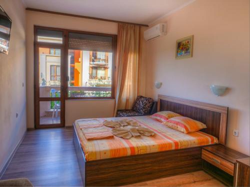 a bedroom with a bed and a chair and a window at Hotel Fantasy Beach in Sveti Vlas